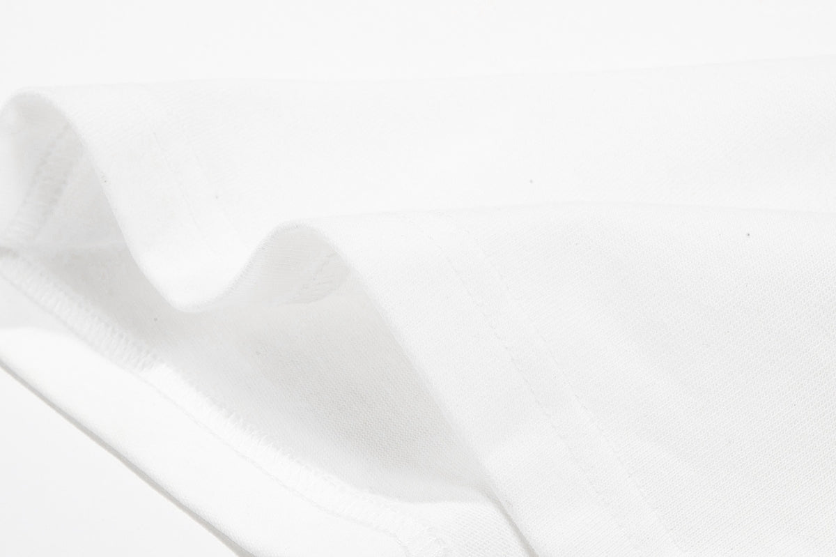 Close-up of white fabric showing a folded edge and stitched seam.