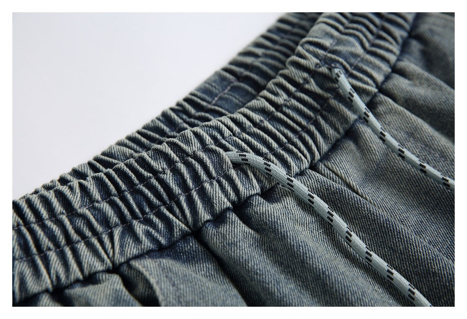 Close-up of the gathered denim waistband with gray patterned drawstrings threaded through it.