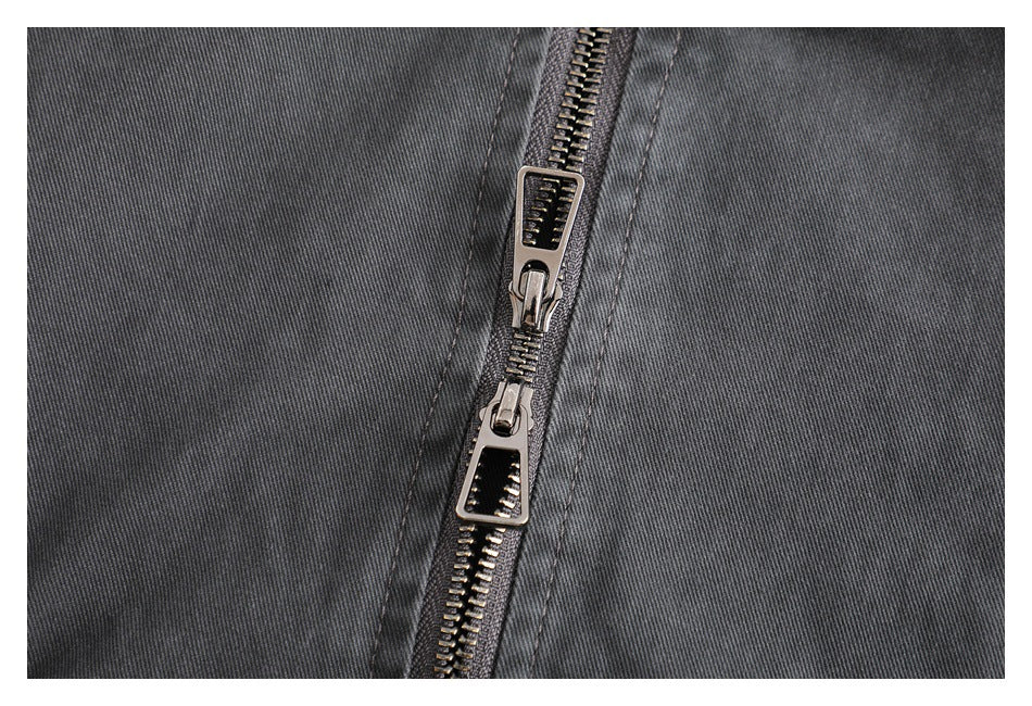 Close-up of the charcoal jacket's front zipper with two metal pulls and visible fabric stitching.