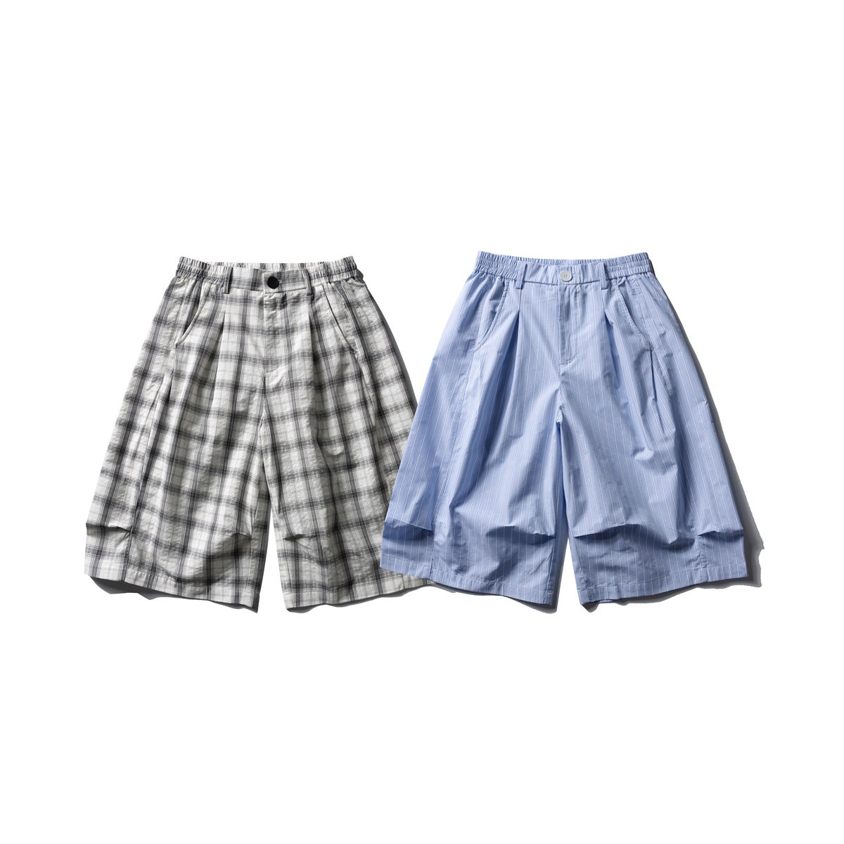 Two pairs of pleated shorts shown from the front: one gray-and-black plaid and one light blue with narrow stripes.