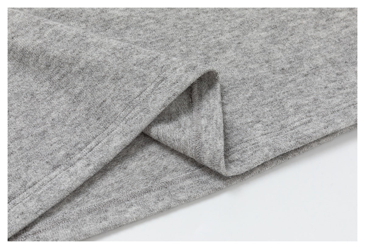 Close-up of a folded seam and stitching on heather gray knit fabric.