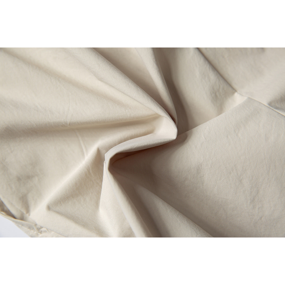 Close-up of cream-colored shorts fabric folded to show its surface and drape.