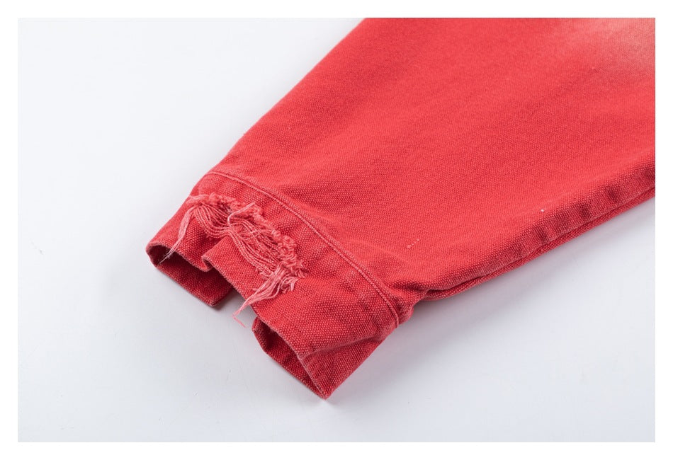 Close-up of a coral-red jacket sleeve cuff with distressed, frayed fabric.