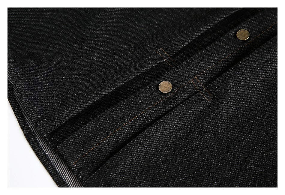 Close-up of black denim with two metal buttons and orange stitching along the placket.