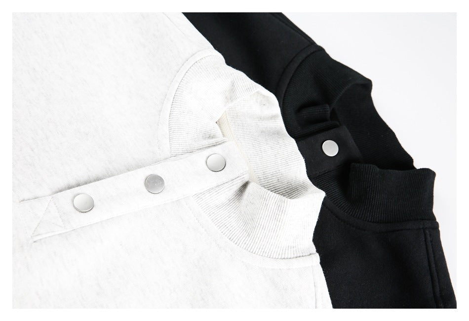 Close-up of light heather gray and black garments showing ribbed neckline trim and snap-button tabs.