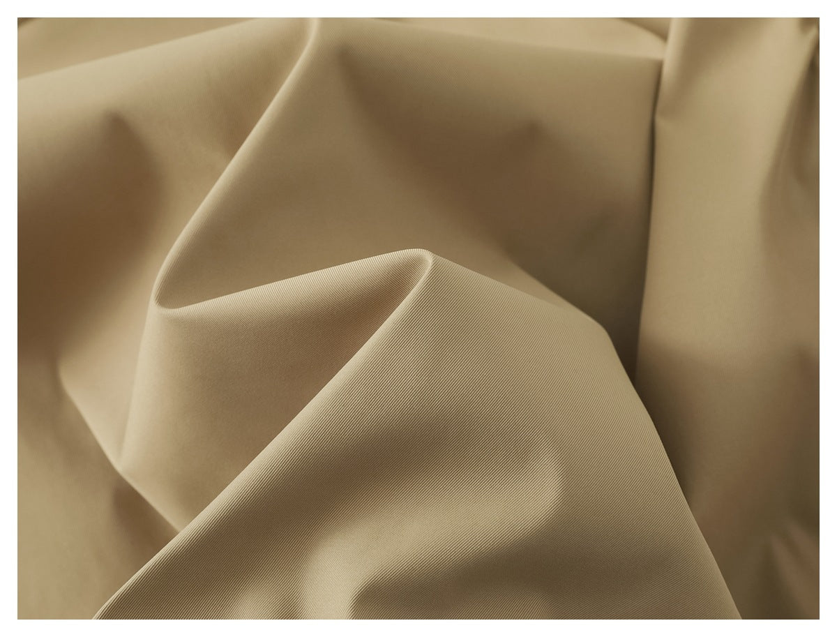 Close-up of beige fabric draped in soft folds, showing its fine surface texture.