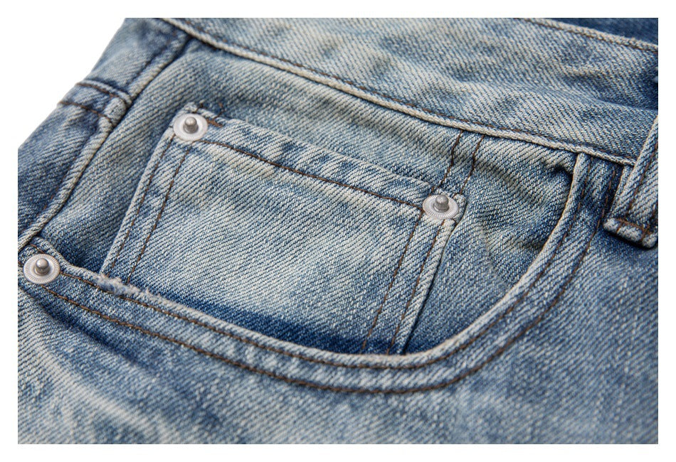 Close-up of a front pocket on light blue washed jeans, with metal rivets and visible stitching.