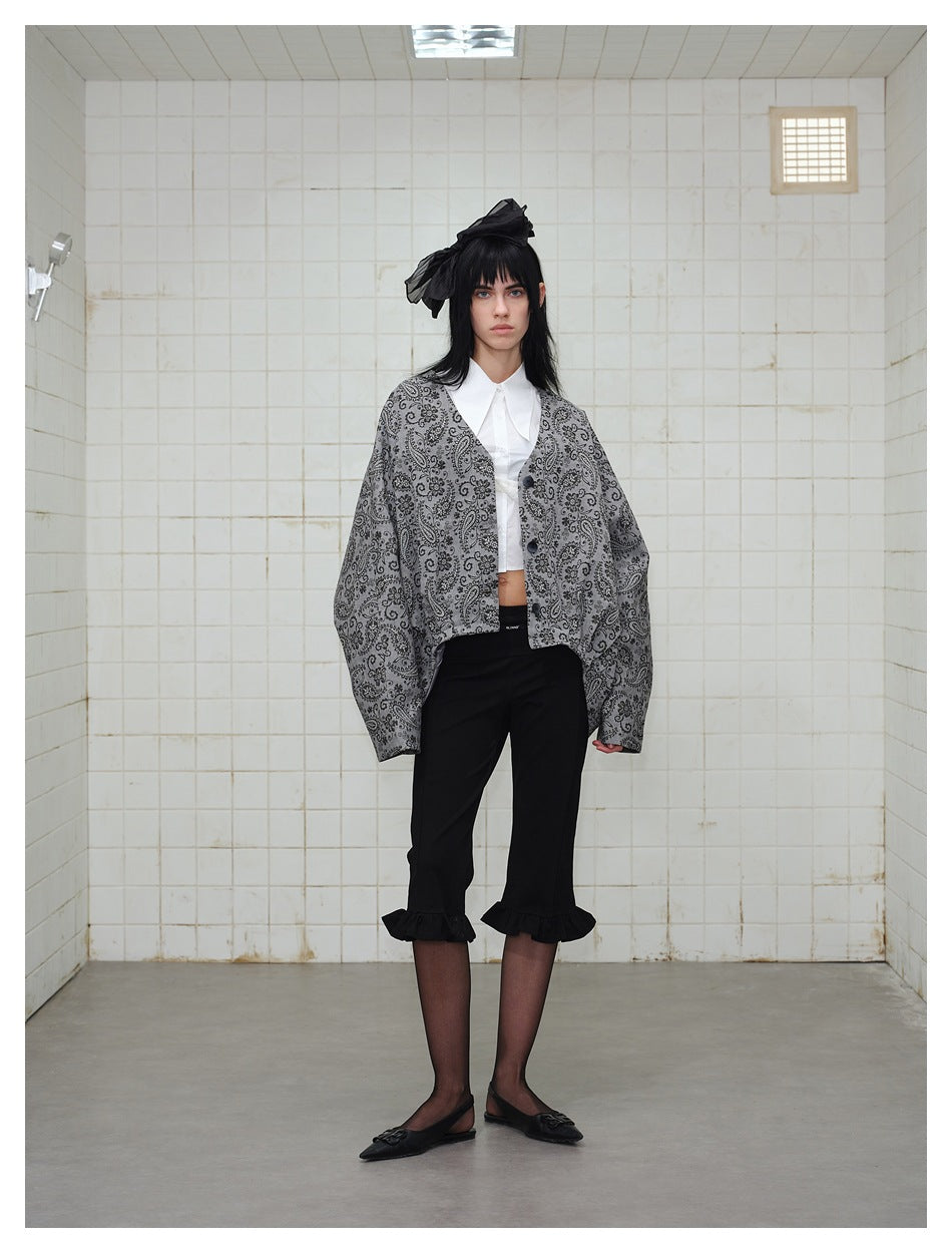 Model wearing the gray paisley oversized jacket open over a white shirt and black cropped pants, front view