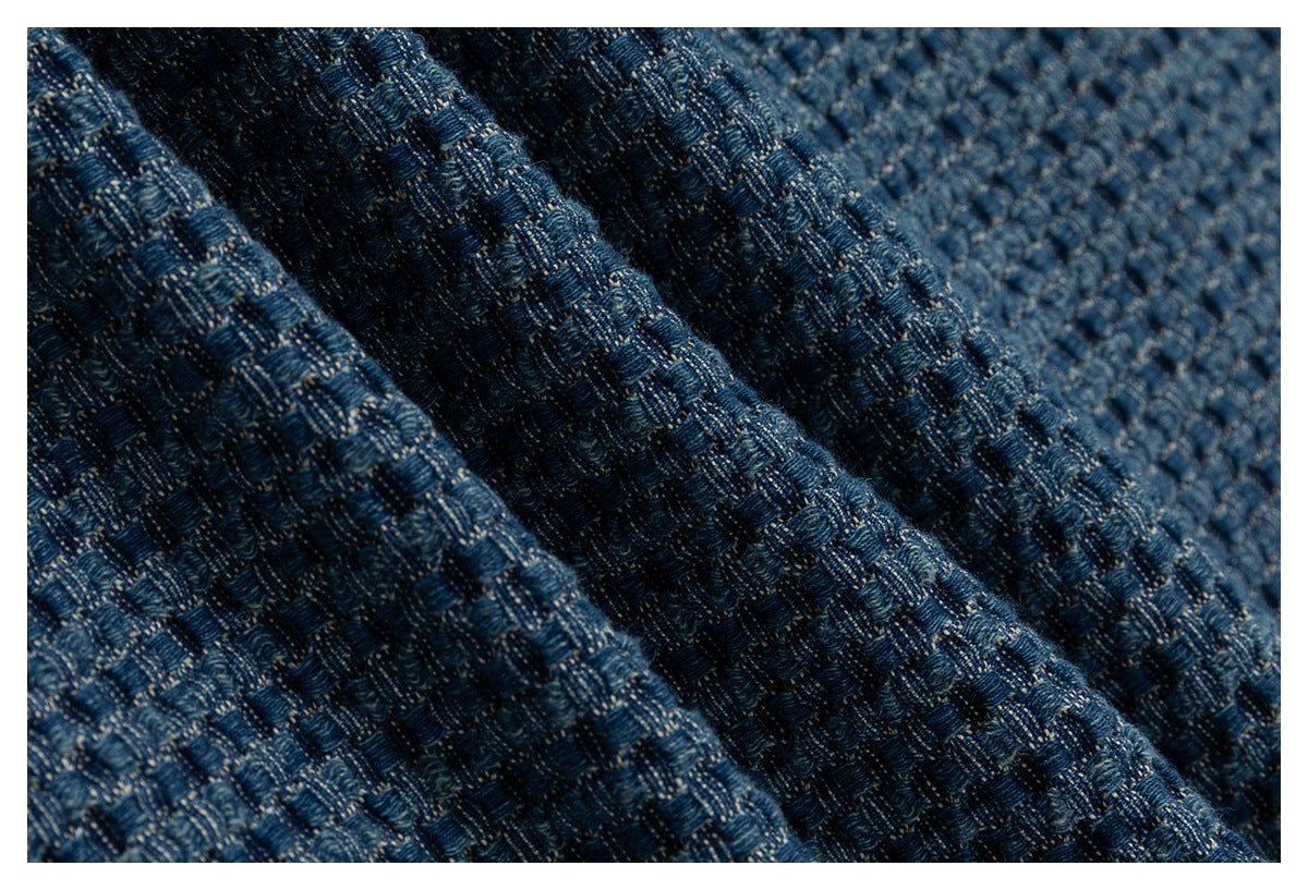 Macro view of blue woven fabric gathered into folds, showing its textured pattern.