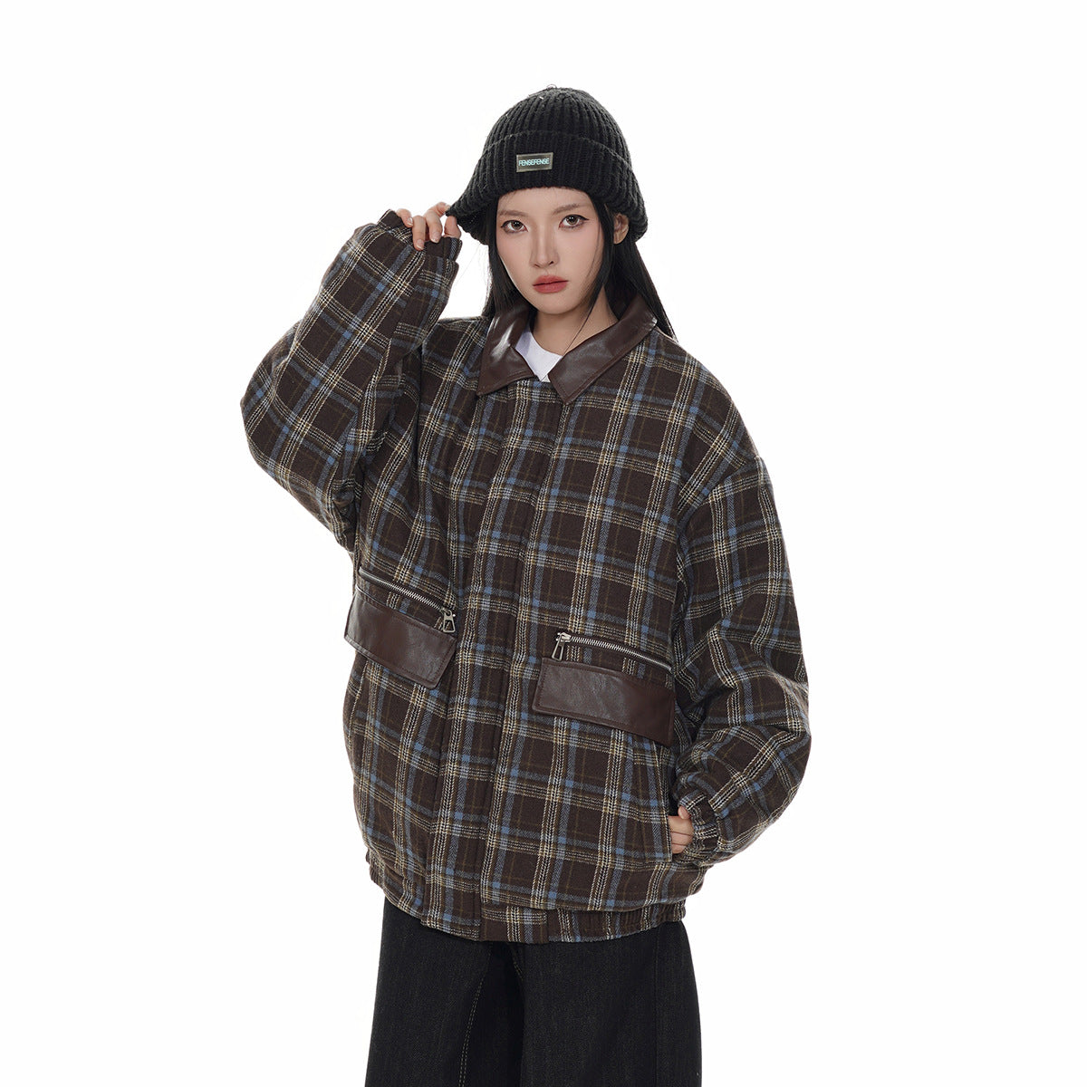 Closer front view of a model wearing a brown plaid jacket with a dark collar and leather-look zip pocket flaps.
