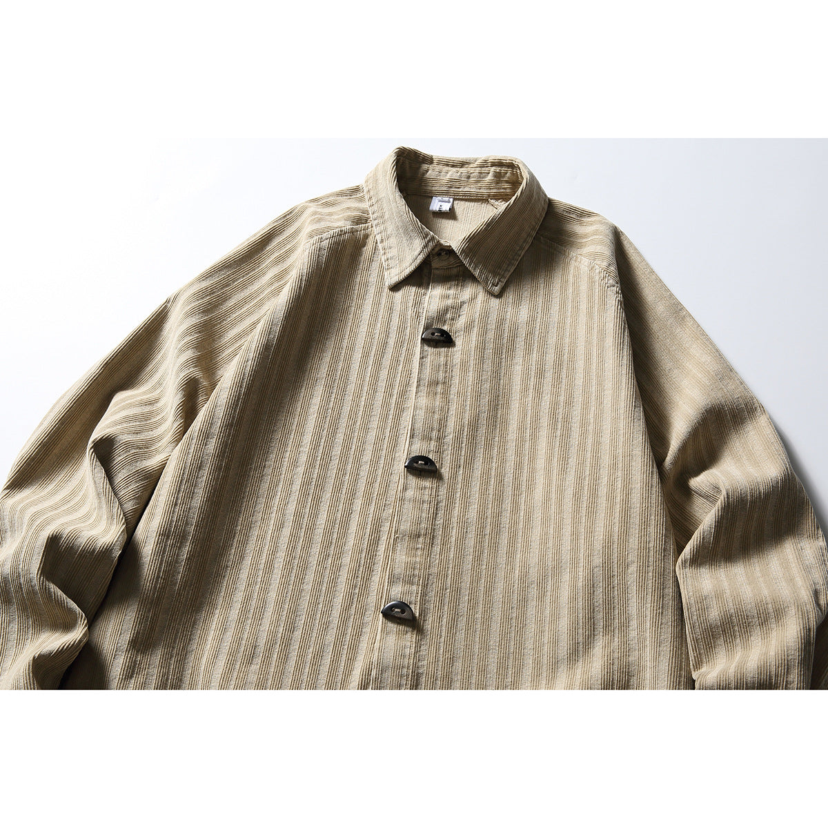 Close-up of a beige long-sleeve button-up shirt with a pointed collar, dark buttons, and narrow vertical stripes.