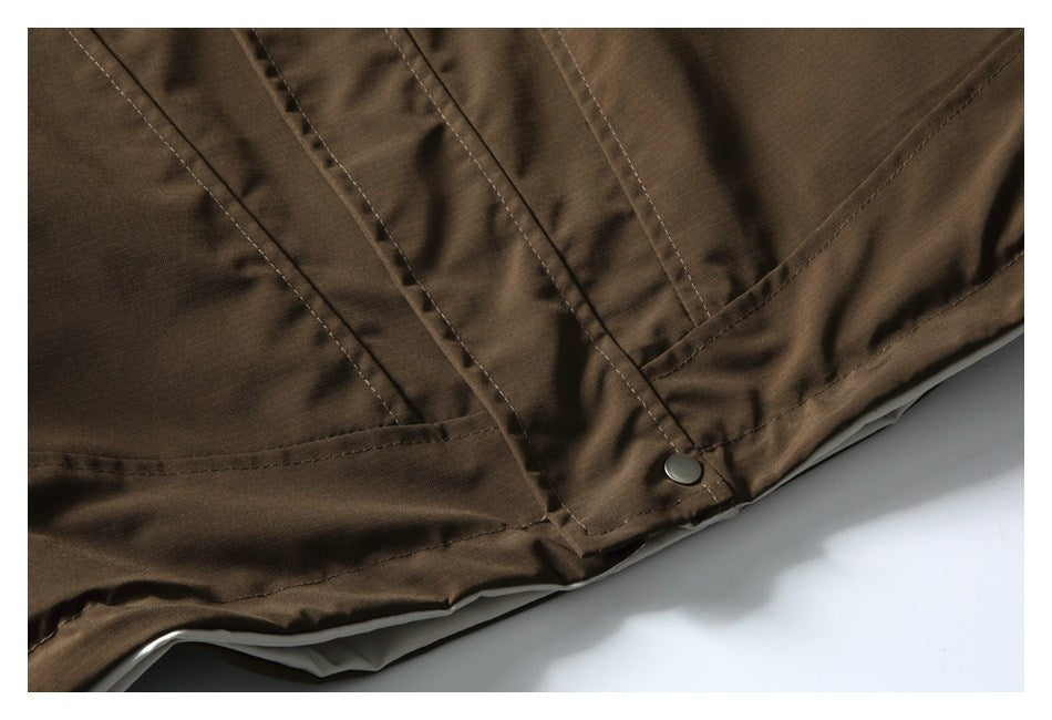 Close-up of a brown garment with stitched panels and a small metal snap fastener.
