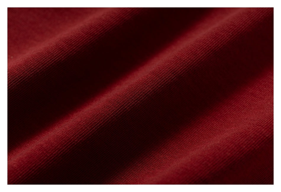 Close-up of deep burgundy knit fabric showing its fine texture and draped folds.