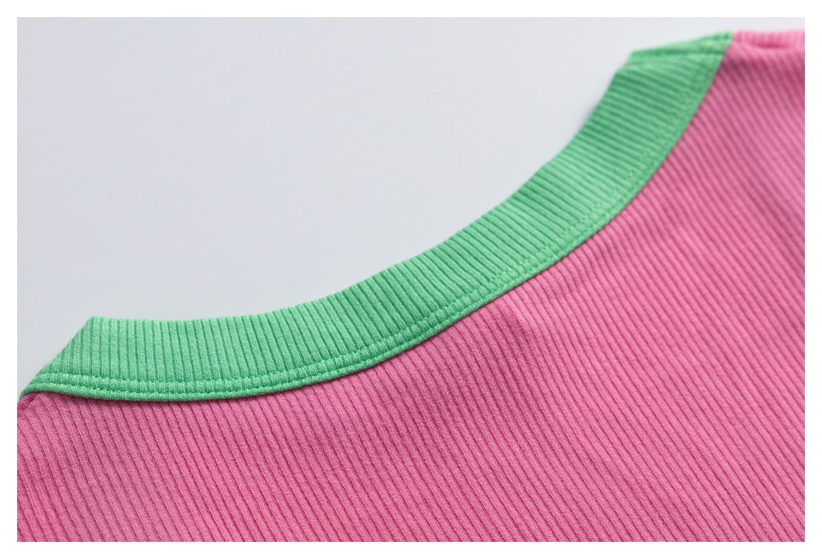 Close-up of a pink ribbed garment neckline with contrasting green ribbed trim.