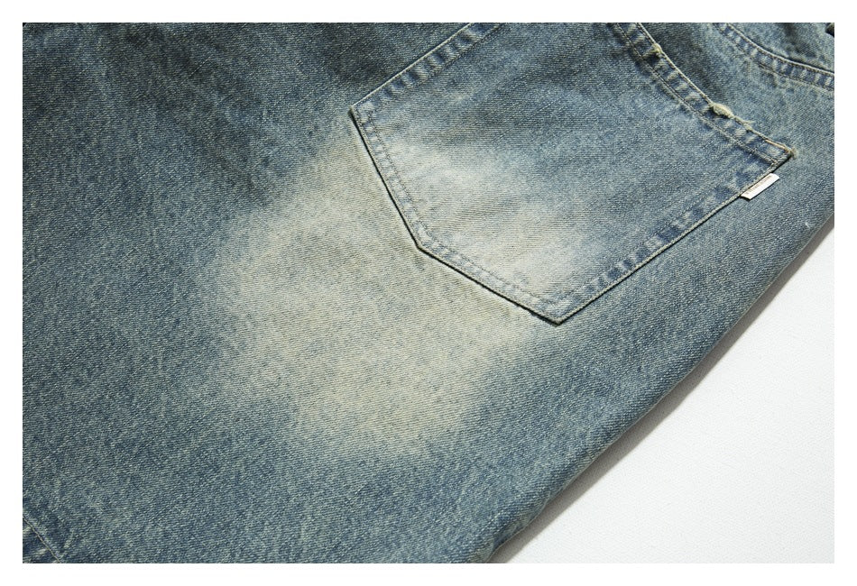Close-up of a rear pocket on faded blue denim jeans, showing contrast stitching and a small white tab.