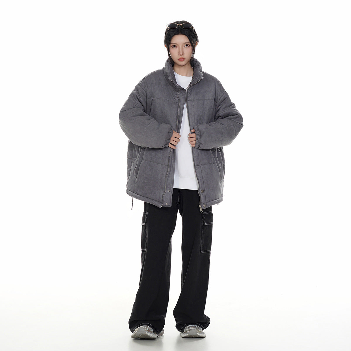 Model wearing an oversized charcoal-gray quilted jacket with a high collar and front zipper, shown full length.
