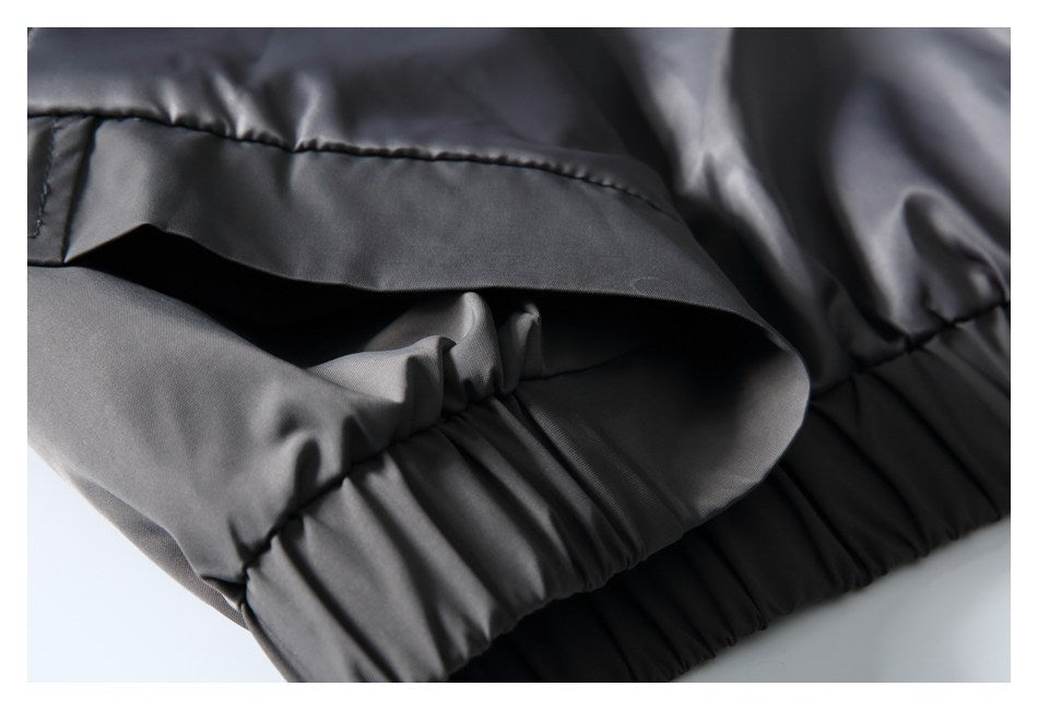 Close-up of the charcoal-gray jacket's gathered elastic hem beneath a stitched flap.