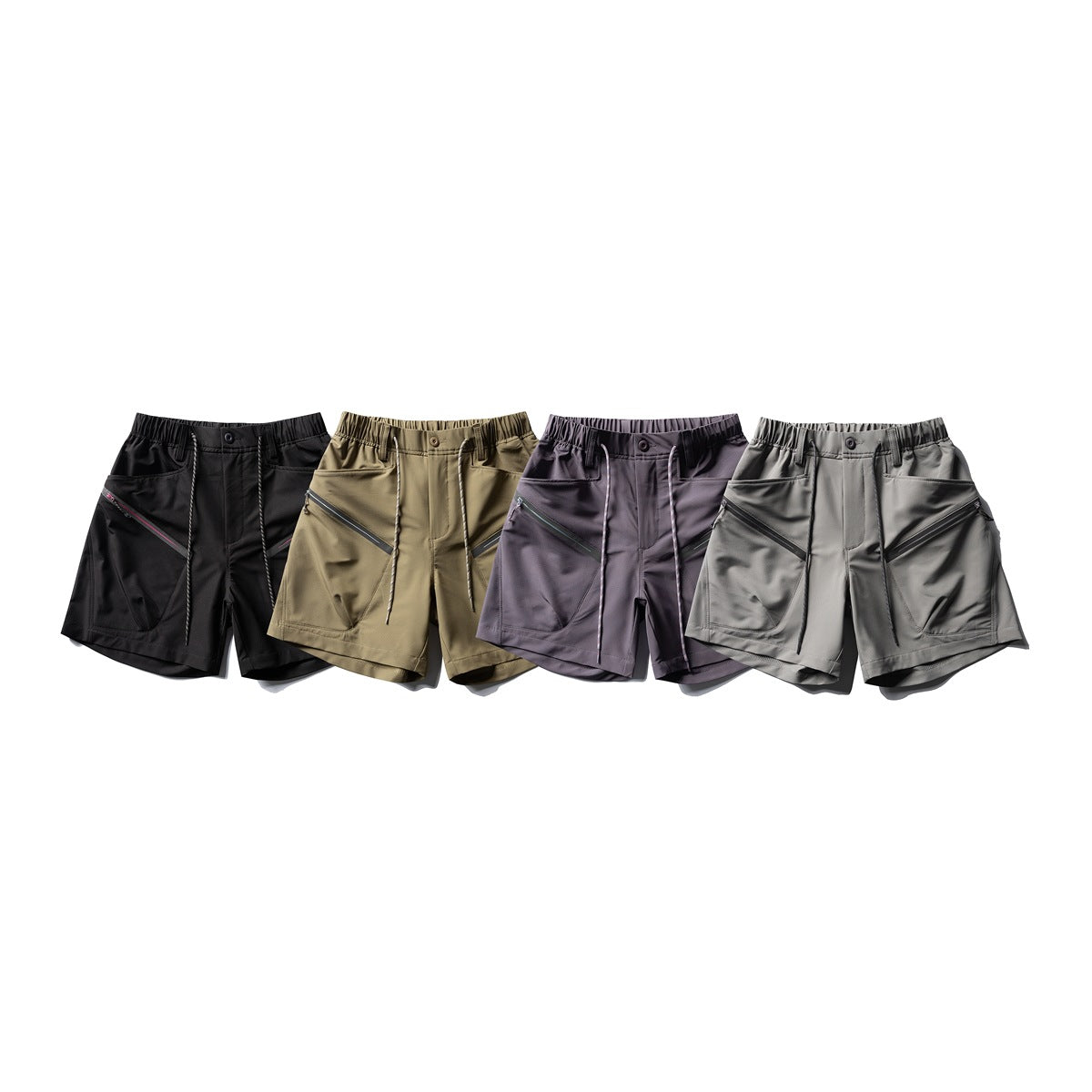 Four pairs of shorts displayed together in black, tan, dark plum, and gray, each with angled zip pockets.