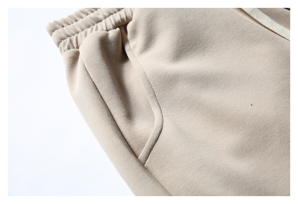 Close-up of the beige shorts' curved side pocket and elastic waistband.