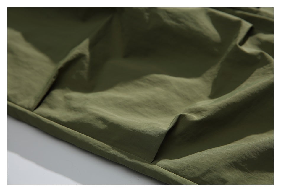 Close-up of stitching and a folded hem on olive-green pants.