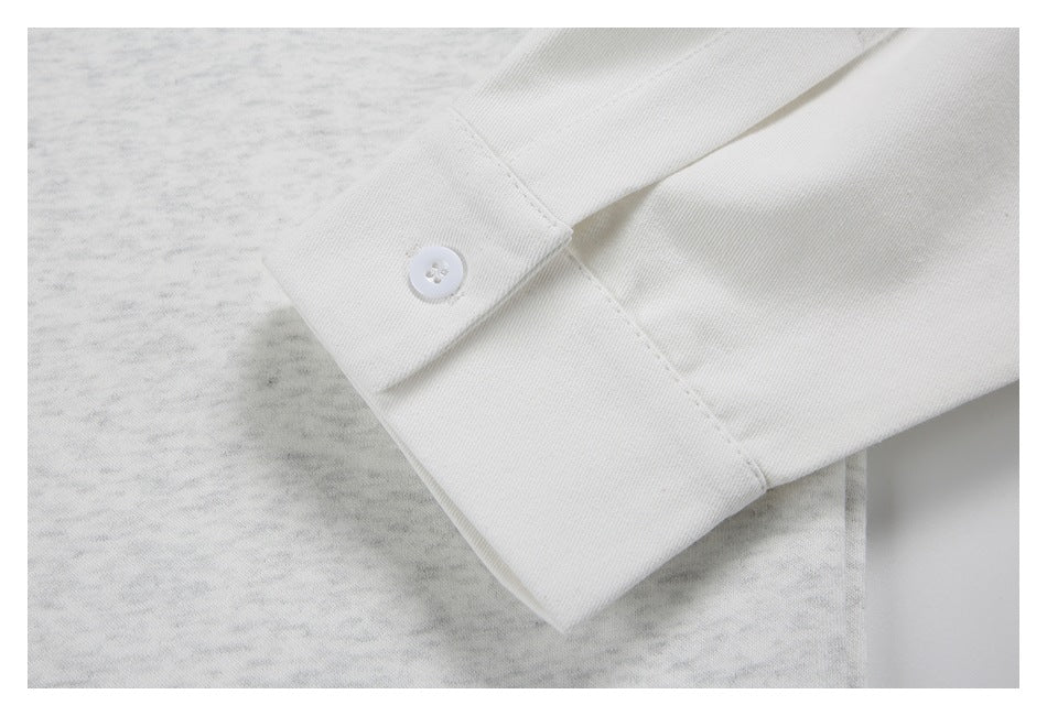 Close-up of a white button and cuff on a light gray heathered garment.