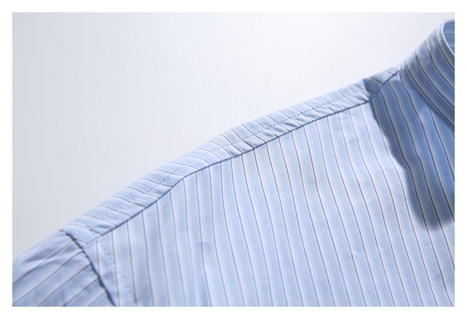 Close-up of a light blue shirt shoulder seam with narrow vertical white stripes.