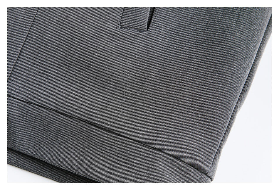 Close-up of charcoal gray woven garment fabric with stitched seams and a folded hem edge.