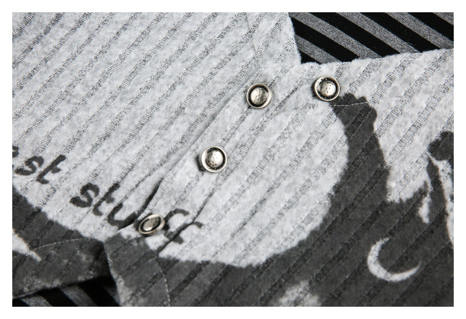 Close-up of metal buttons on a light gray striped garment with part of a dark graphic print.
