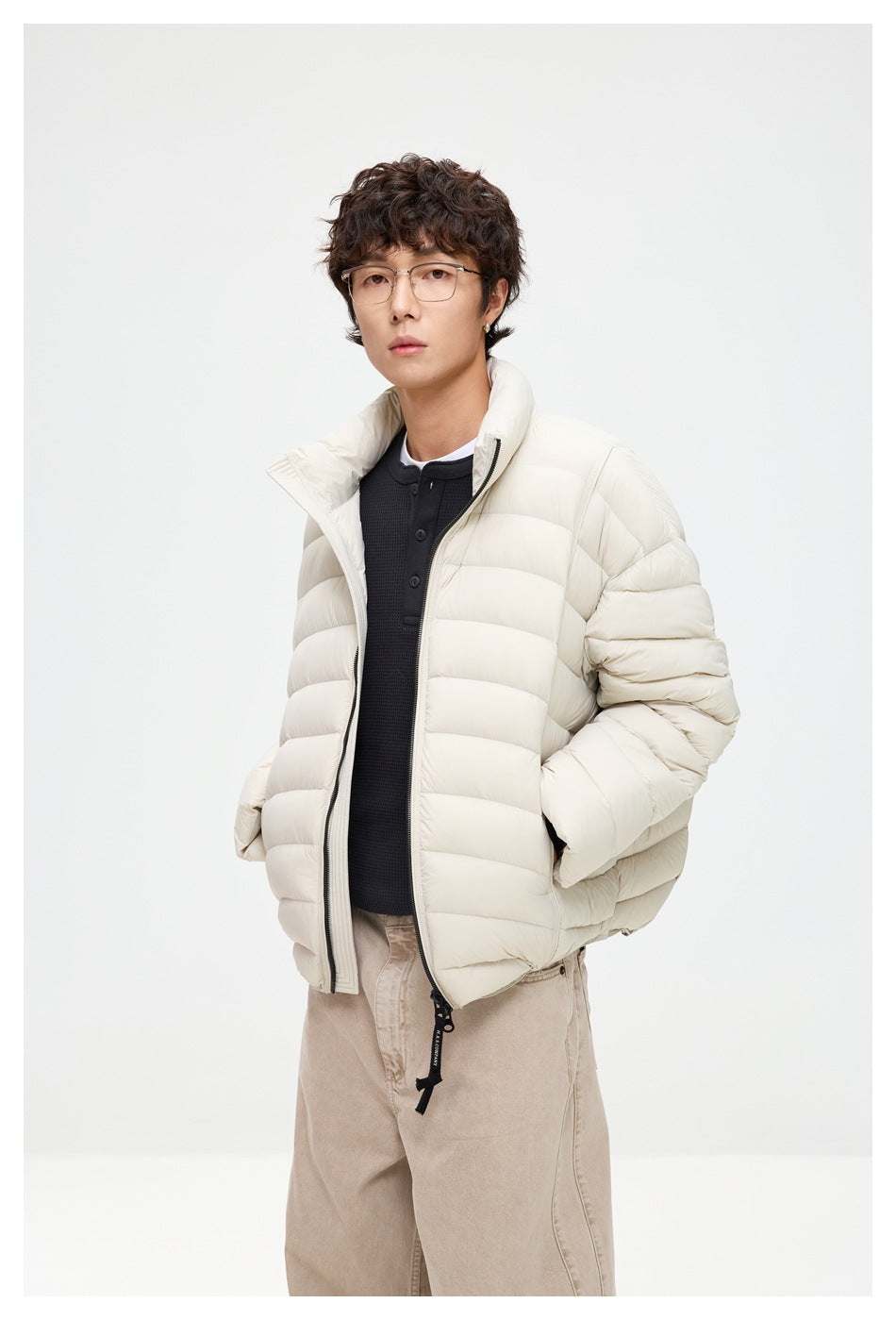 Model wearing an off-white quilted puffer jacket unzipped over a dark top, shown from a slight angle.