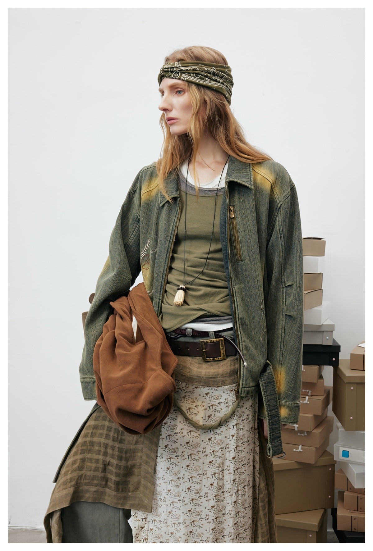 Model in a distressed olive jacket with a zip front and chest pocket, layered over an olive top.