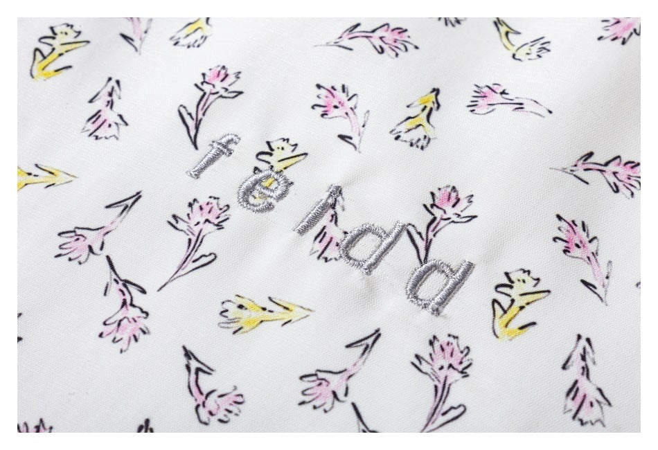 Close-up of the white floral-print fabric with gray embroidered lettering.