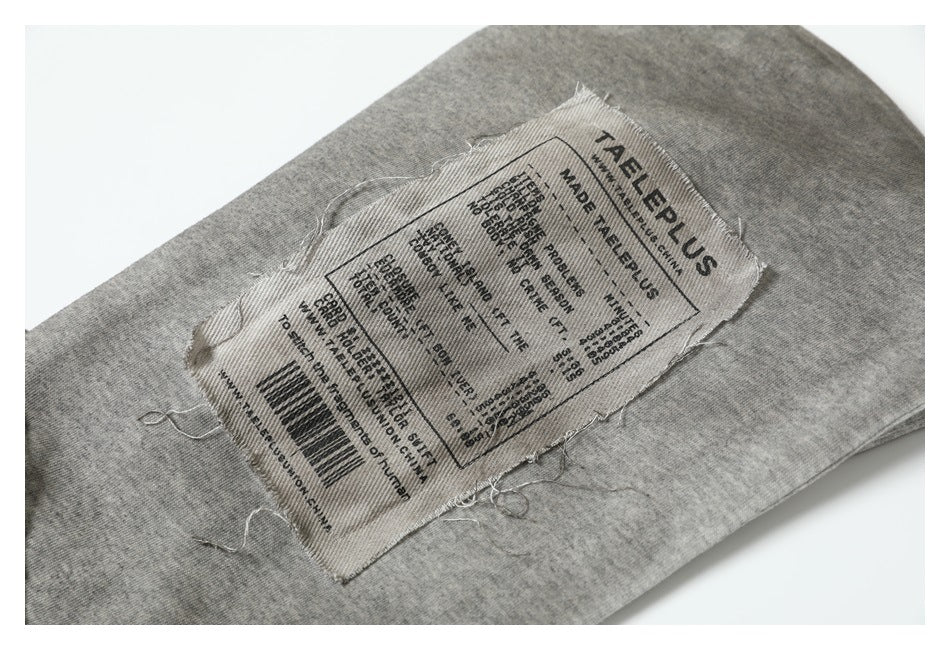 Close-up of a sewn fabric label with English text on a heather gray garment.