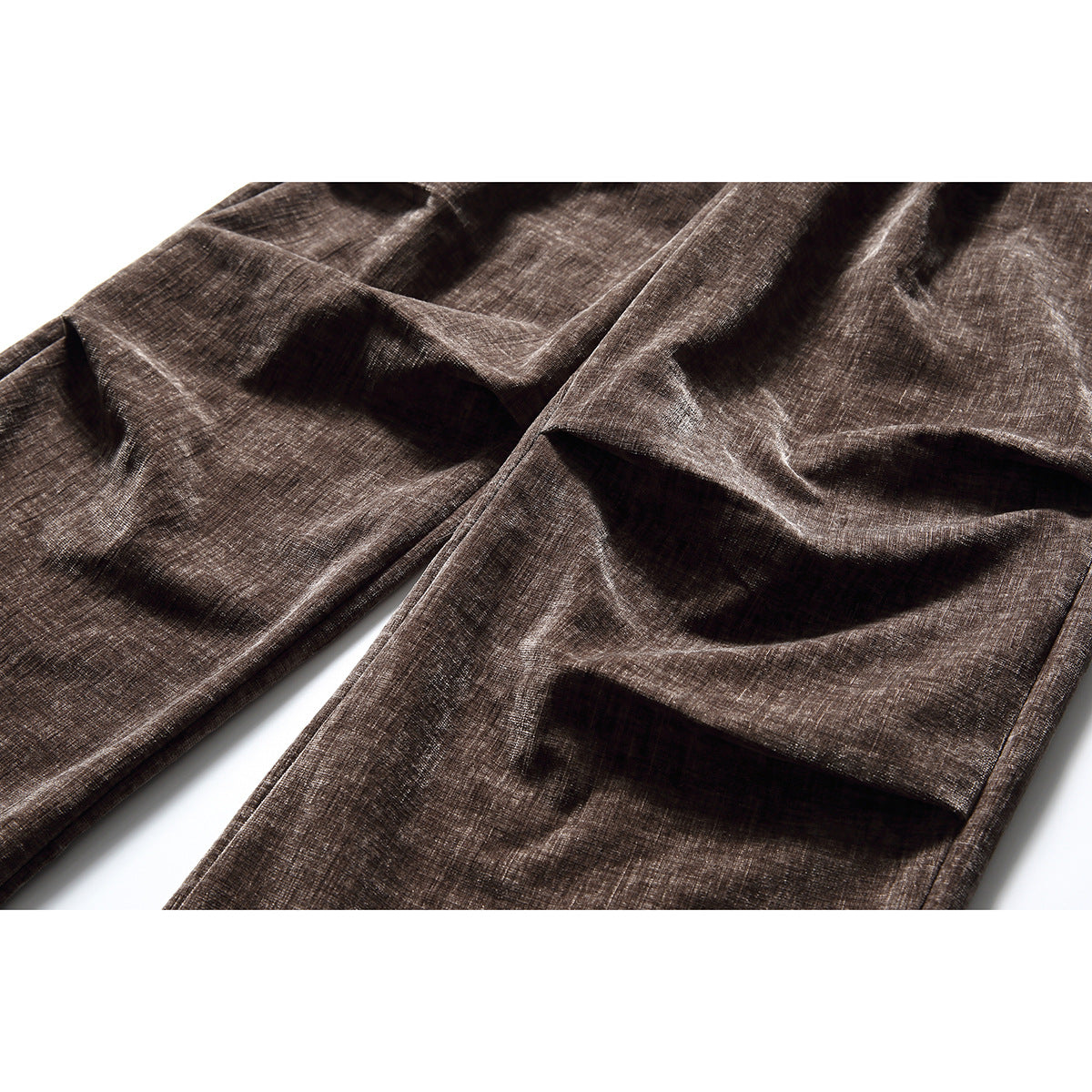 Close-up of brown textured trouser legs with prominent front pleats and folds.