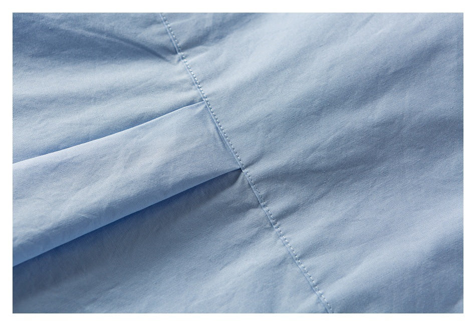 Close-up of light blue garment fabric showing a diagonal seam and overlapping folded panel.
