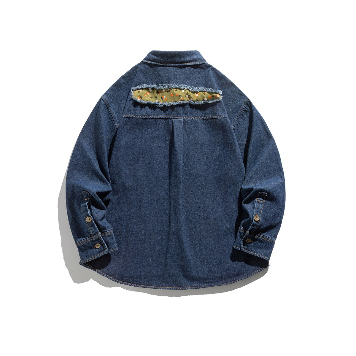 Back view of a dark blue denim shirt laid flat, featuring a frayed floral fabric insert across the upper back.