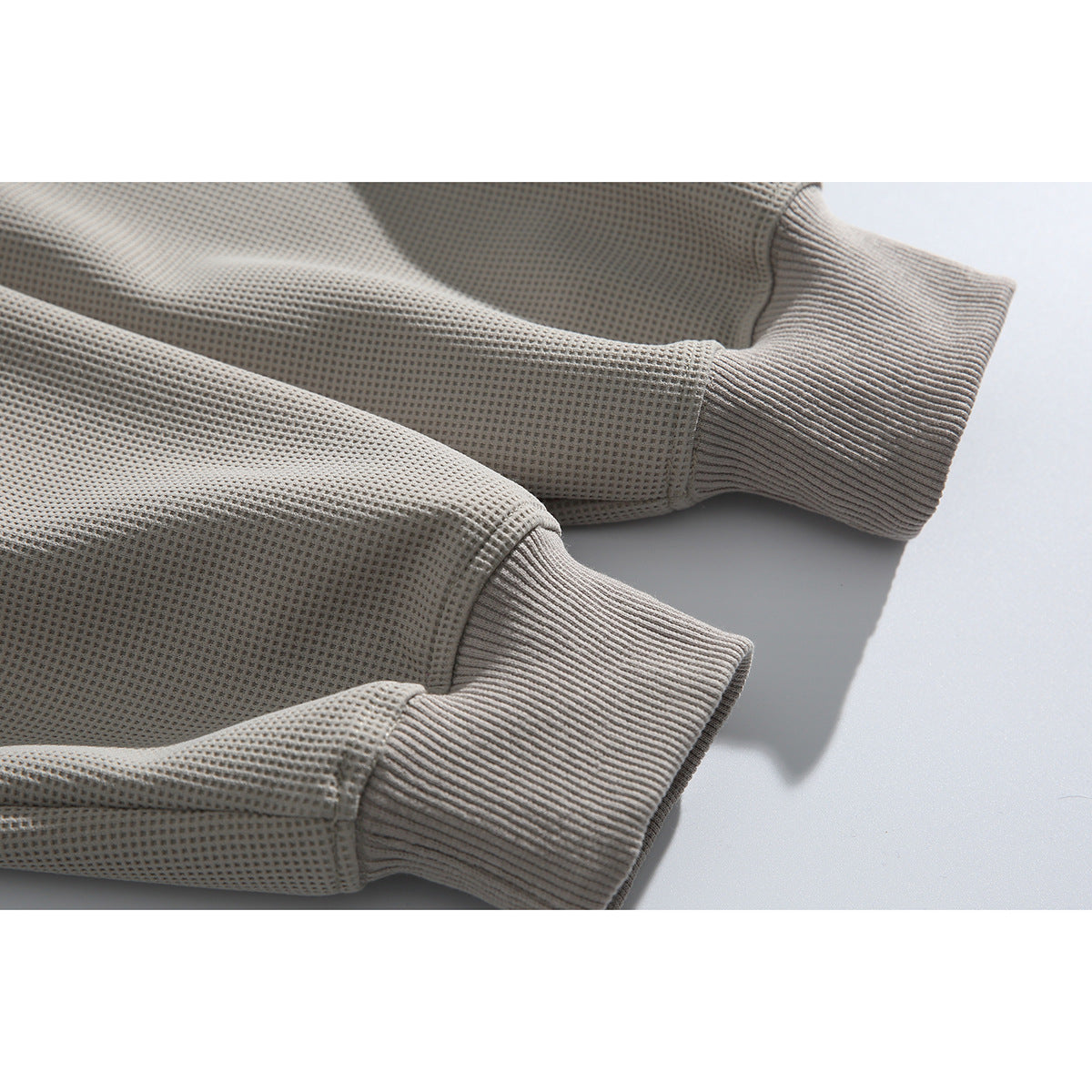 Close-up of the ribbed cuffs and waffle-textured sleeves of a light gray sweatshirt.