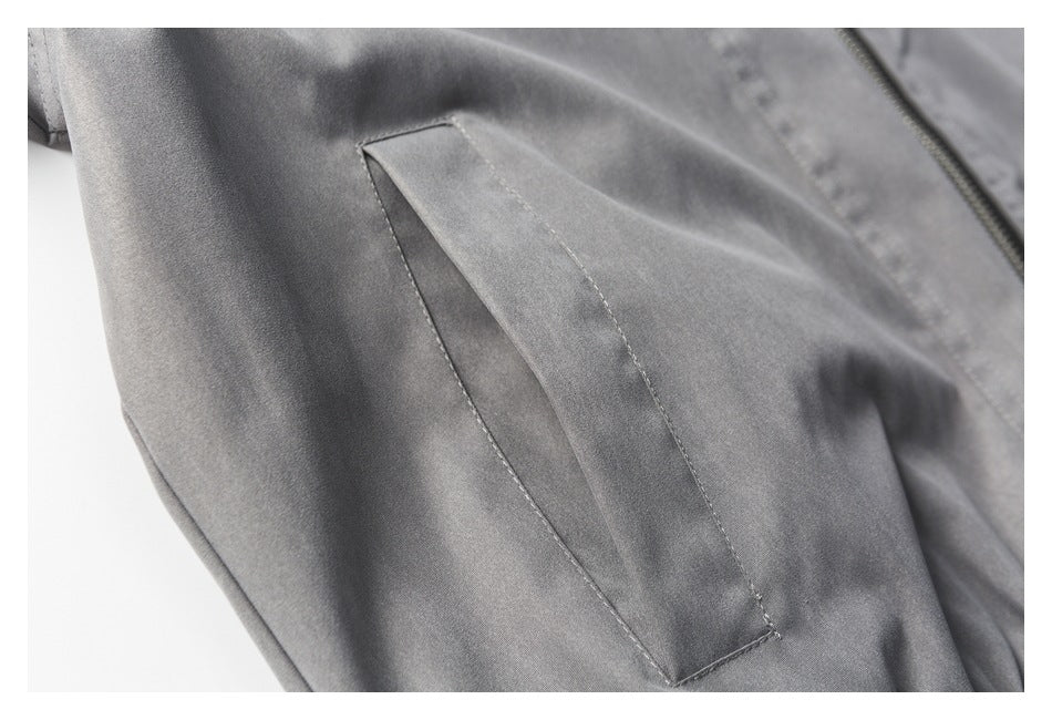 Close-up of the gray jacket's angled welt pocket and visible edge of the front zipper.