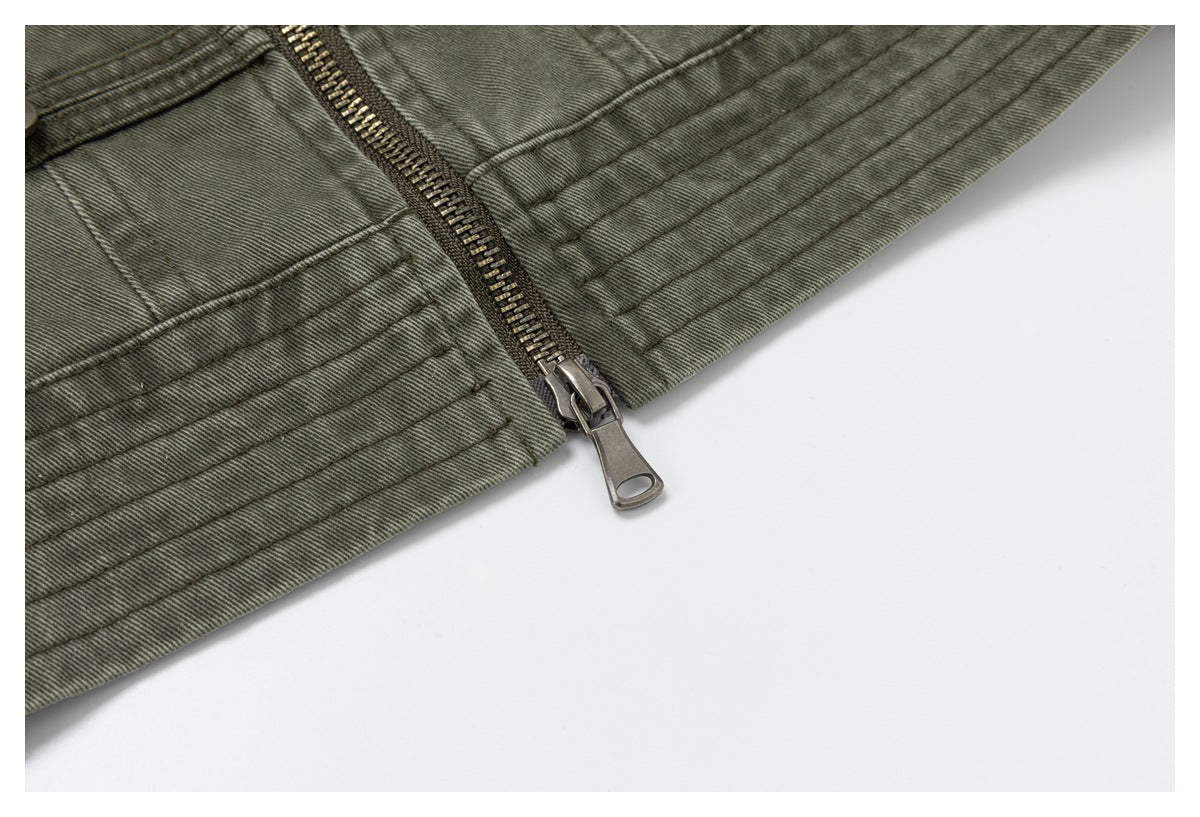 Close-up of the olive-gray jacket hem and metal zipper pull with parallel stitched bands.