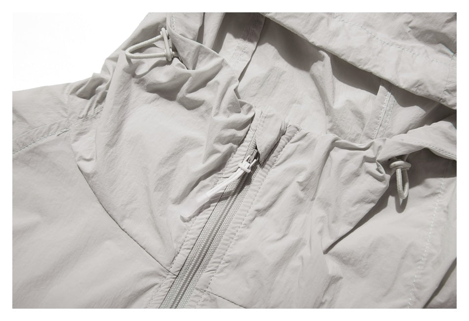 Close-up of the light gray jacket's front zipper, hood drawcords, and stitched panels.