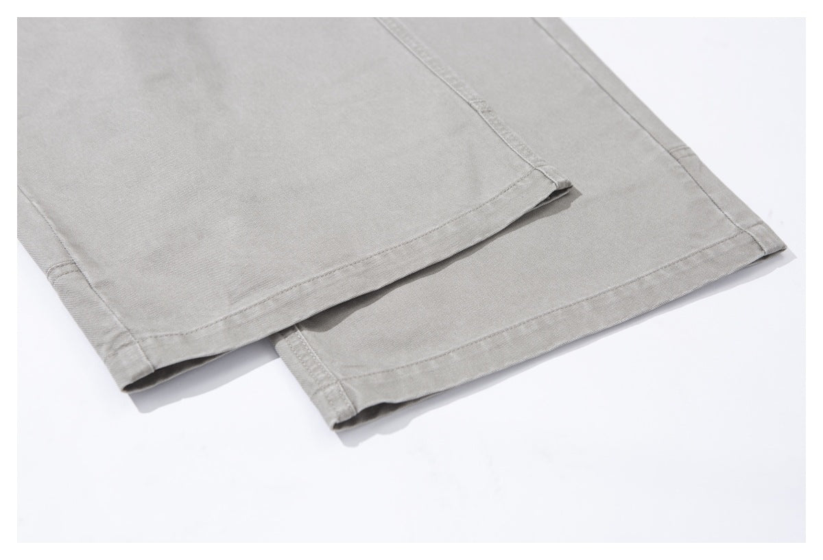 Close-up of the wide stitched hems on light gray trousers.