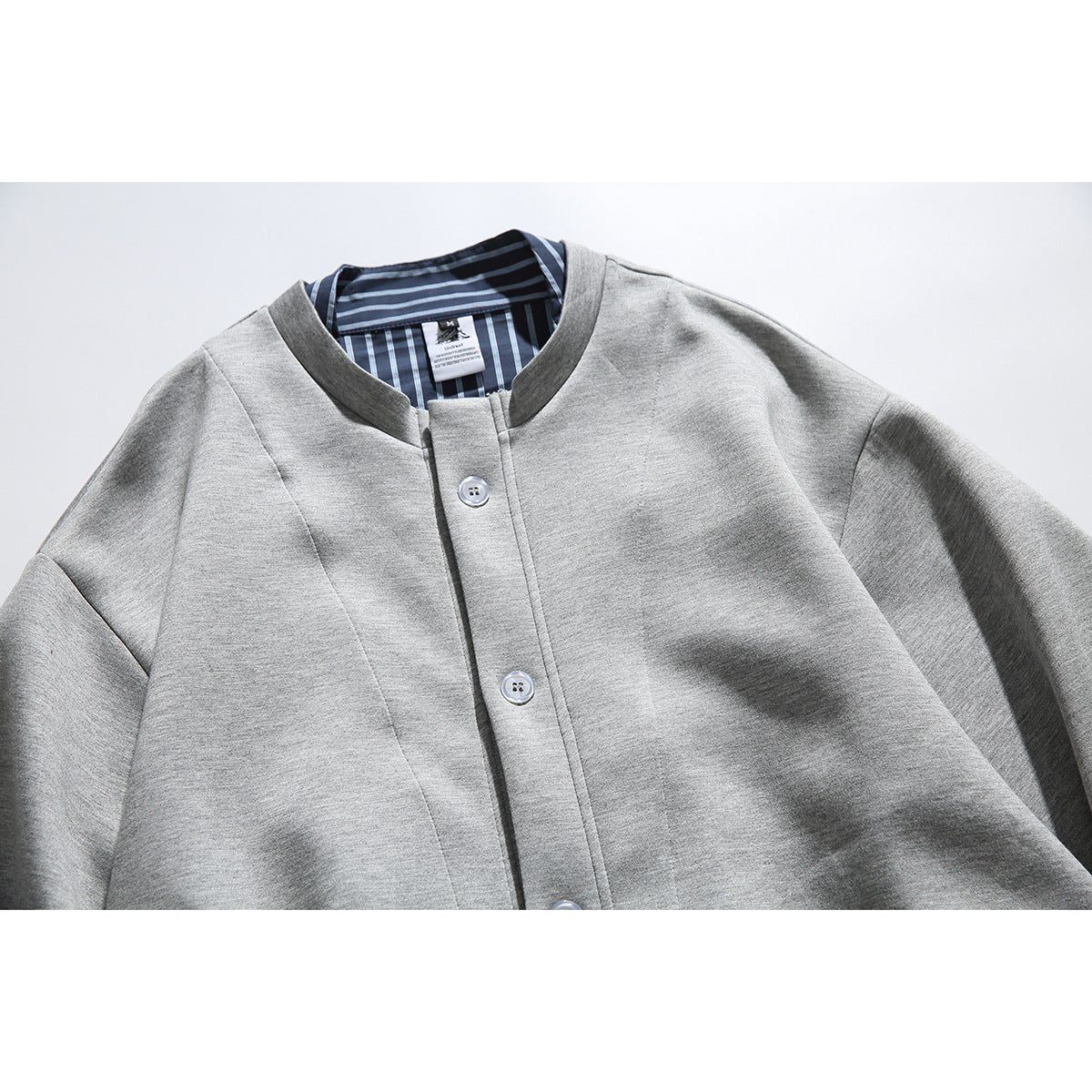 Close-up of a light gray button-front jacket with a dark striped inner collar.