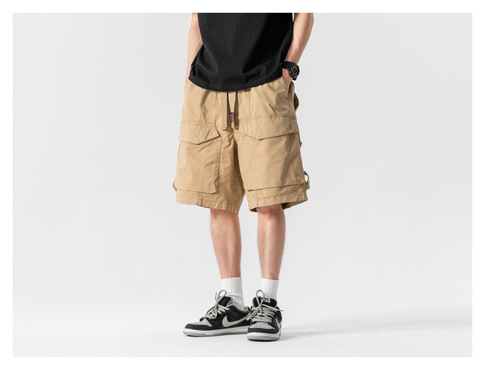 Front view of a model wearing tan cargo shorts with large flap pockets and a black T-shirt.