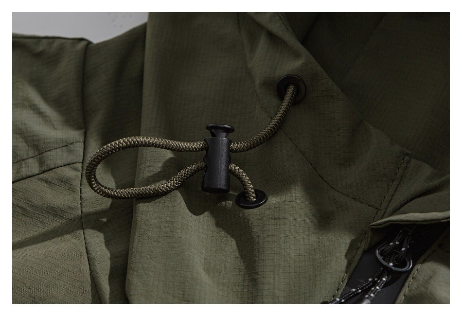 Close-up of an olive garment's braided drawcord, cord lock, and black eyelets.