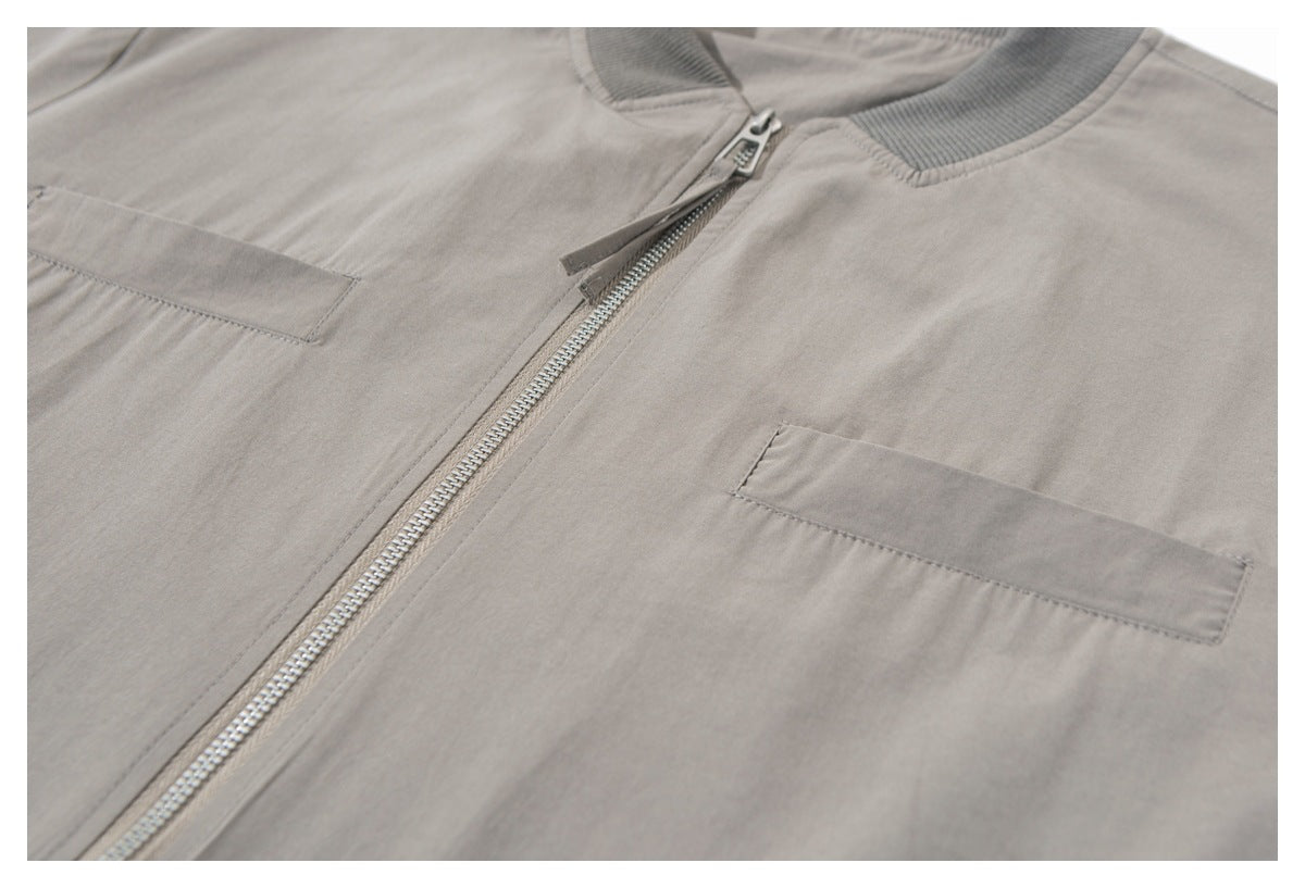 Angled close-up of a taupe-gray jacket with a silver zipper and rectangular chest pockets.