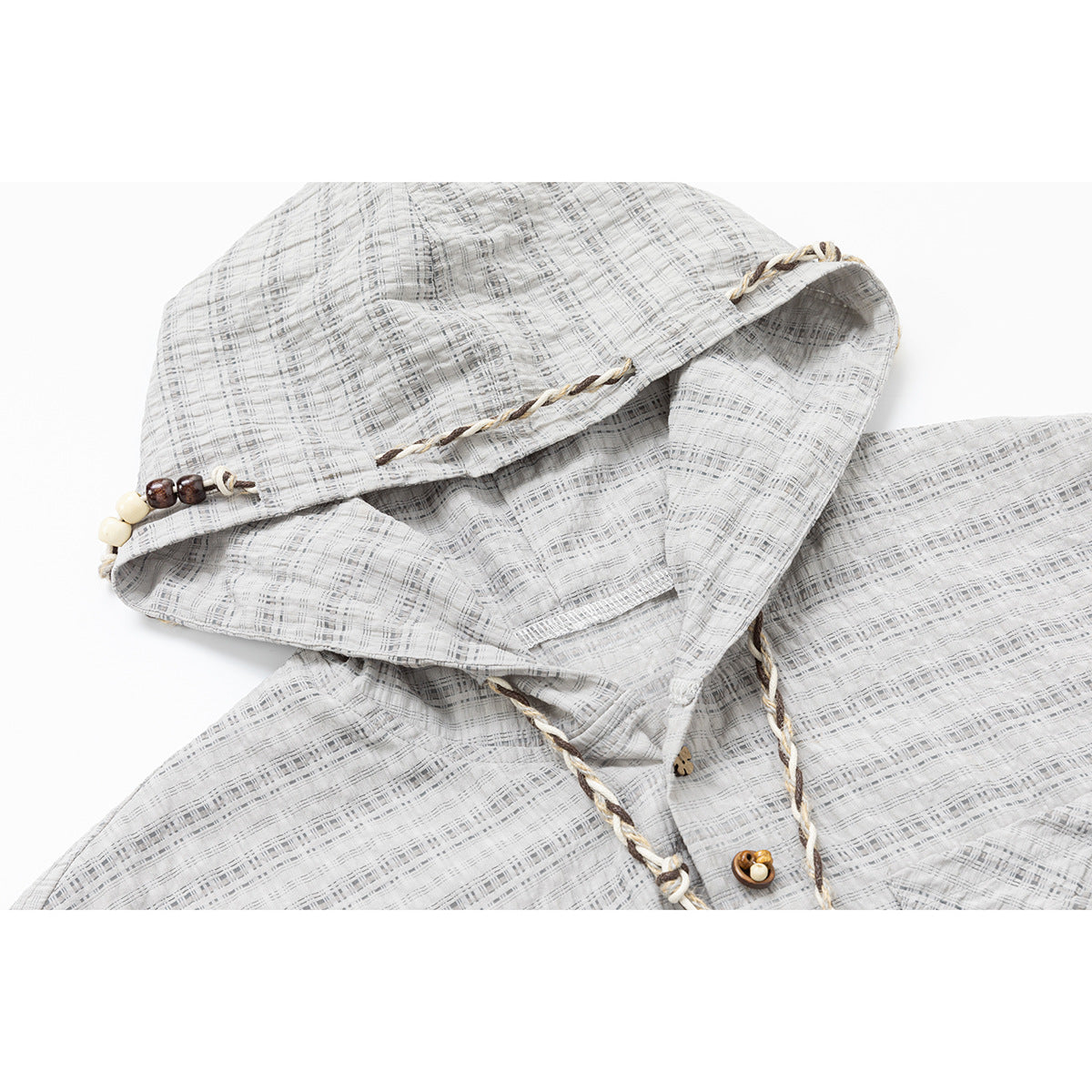 Close-up of the jacket's gray plaid hood, braided edging, beaded drawstrings, and decorative button.