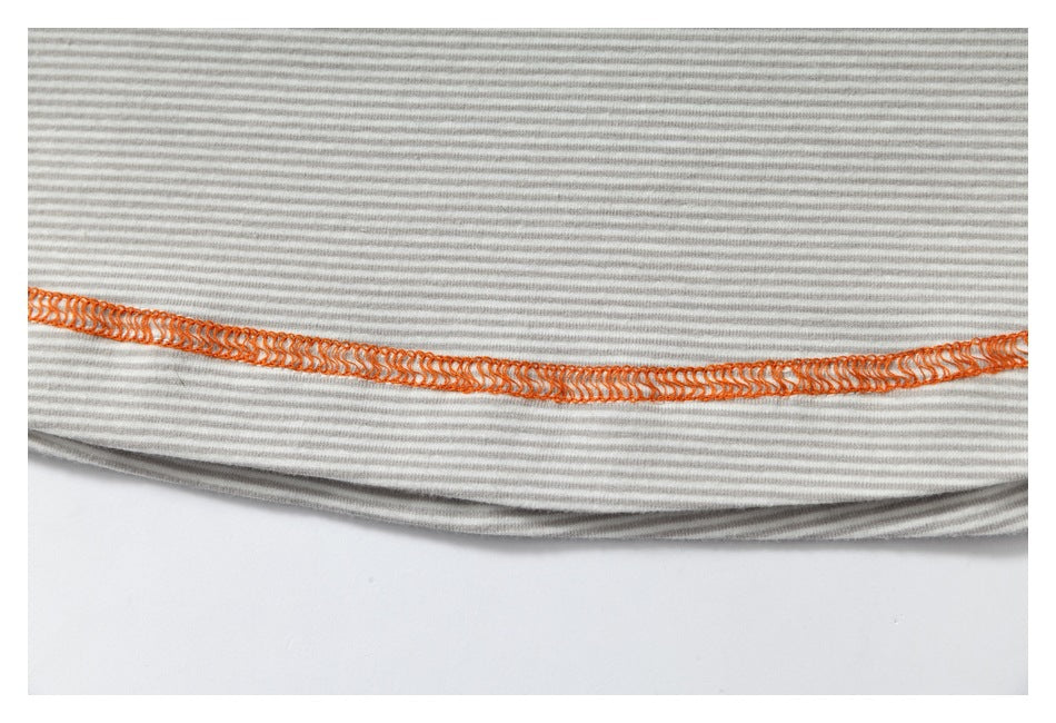 Close-up of a gray-and-white striped garment hem with bright orange overlock stitching.