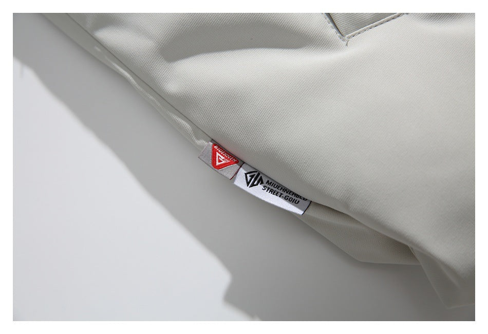 Close-up of a white garment seam with a red logo tab and a white label bearing black text and a logo.