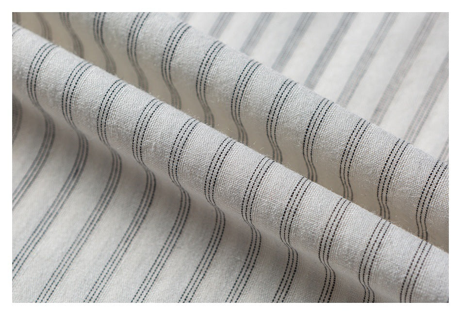 Close-up of softly folded light gray fabric with narrow dark stripes and visible woven texture.