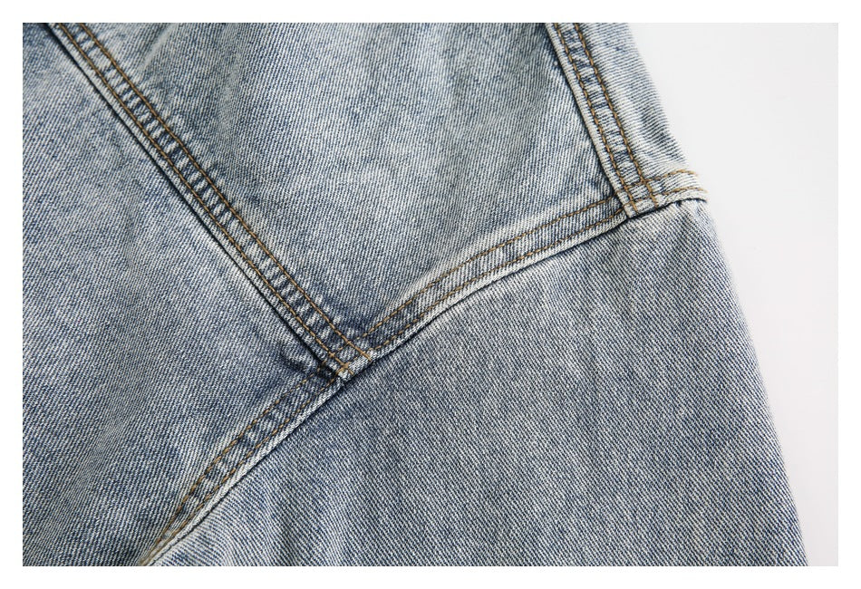 Close-up of intersecting double-stitched seams on light-wash denim.