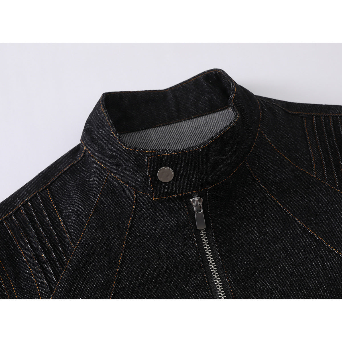 Close-up of a black denim jacket’s stand collar, silver snap, front zipper, and contrasting topstitching.
